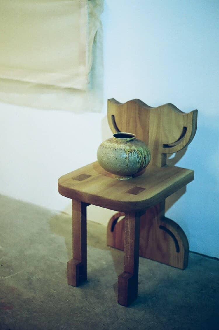 Wooden chair with a vase on top against a plain wall. Photo credit: Giulia Ricciotti